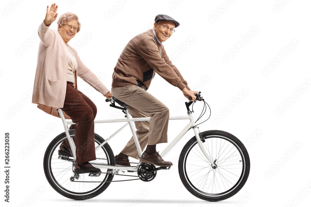 Naklejka premium Senior woman and man riding a tandem bycicle and waving