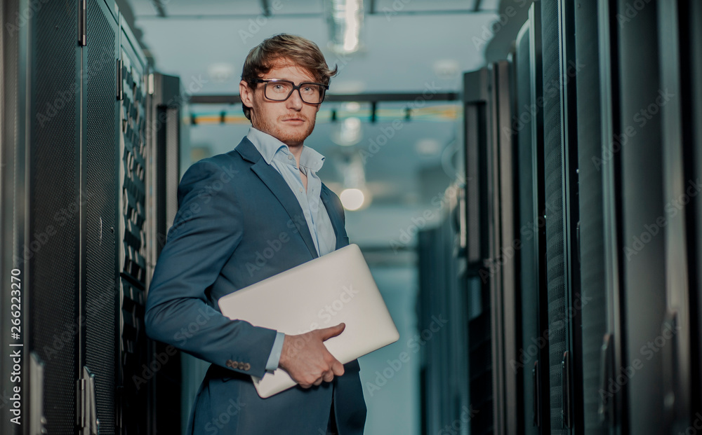 Young it engeneer business man with thin modern aluminium laptop in network server room Young it engeneer business man with thin modern aluminium laptop in network server room