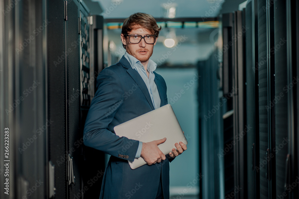 Fototapeta premium Young it engeneer business man with thin modern aluminium laptop in network server room