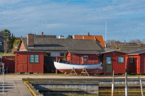 old fishing boat in front of red sheds