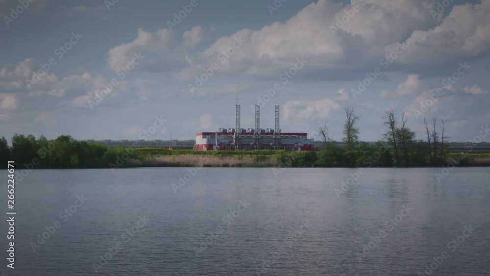 Gas power plant on the river Bank against the background of beautiful spring clouds and blue sky Gas power plant on the river Bank against the background of beautiful spring clouds and blue sky