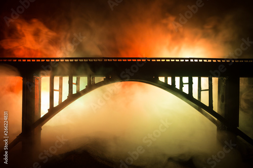 Fototapeta Naklejka Na Ścianę i Meble -  Artwork decoration. Silhouette of powerful metallic bridge at night with foggy backlight. Silhouette of person standing on bridge.