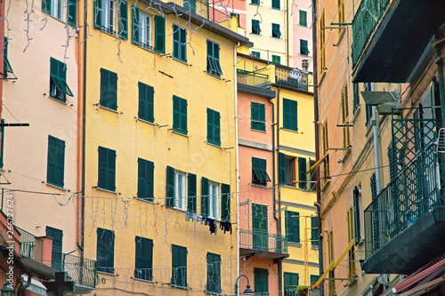 facade of yellow and pink houses of Riomaggiore with green windows with wooden shutters and balconies , Cinque Terre, Liguria, Italy