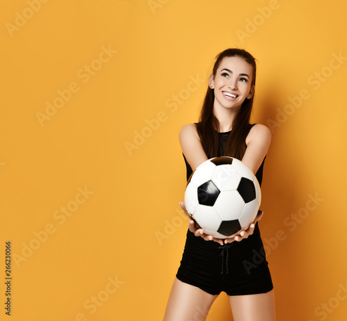 Fan sport woman player in black uniform handed us the soccer ball and smiles on background with free text copy space © Dmitry Lobanov