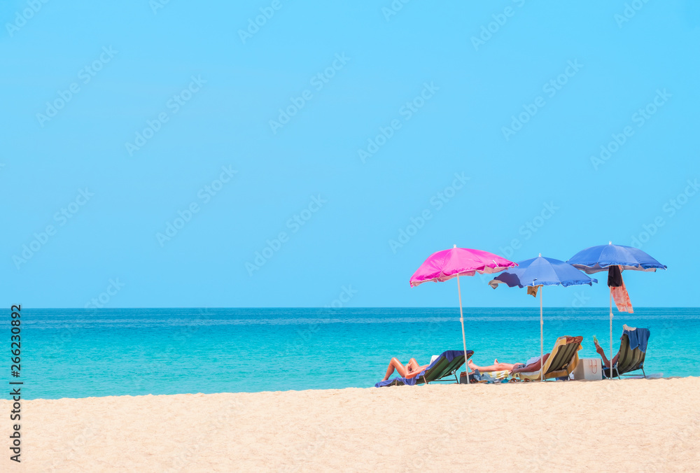 People sunbathing and relaxing on beach chairs. Sea view and blue sky. Summer background -  Image
