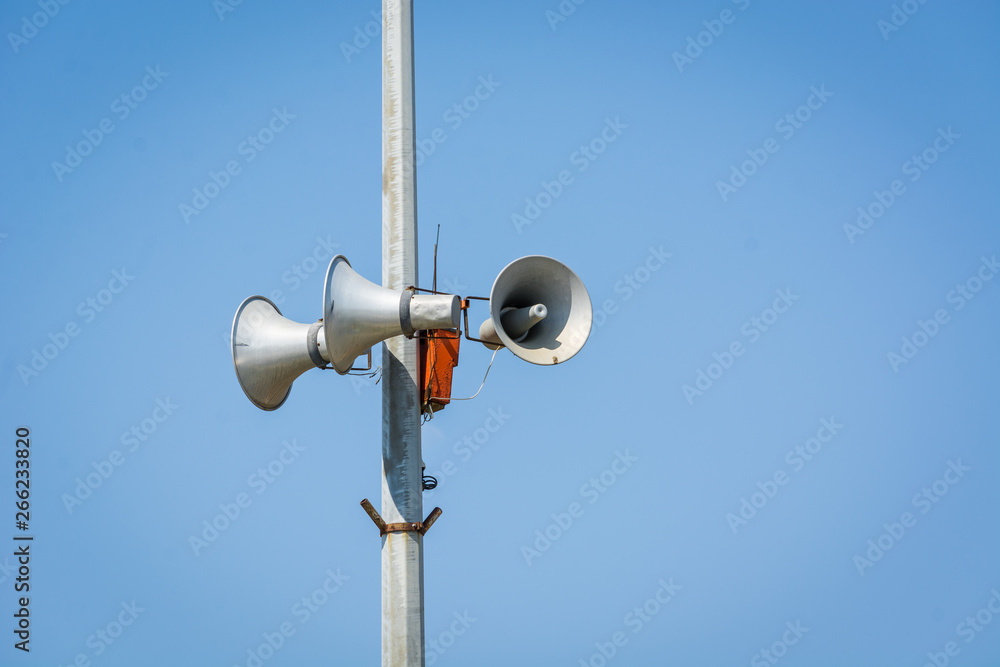 Three loudspeakers on pole against blue sky. Three loudspeakers on pole against blue sky.