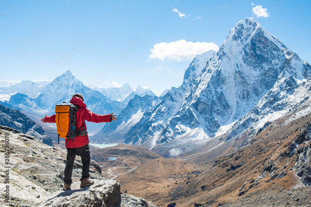 Trekker standing at the edge of the mountain cliff and looking to the beautiful view of Mt.Ama Dablam (6,812 m) and Cholatse (6,440 m) view on the way to Cho La pass, Nepal.