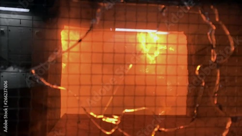 View inside an incinerator, somewhat out of focus due to the intense heat. 
Reflection of the background through the safety glass.
