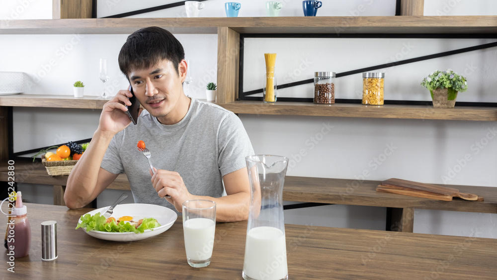Young handsome Asian eating breakfast