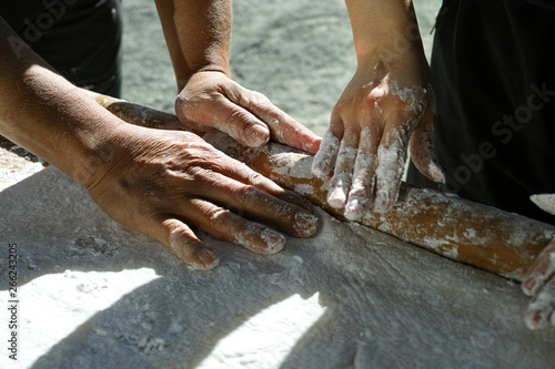 two pairs of hands rolling and pressing mochi flat