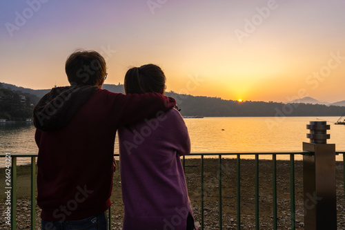 Asian woman and man standing together and looking far away at sun moon lake at sunset time, Selective focus, Copy space.