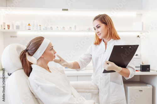Young pretty woman came to a beauty salon and consults with a beautician on anti-aging treatments. Self care concept