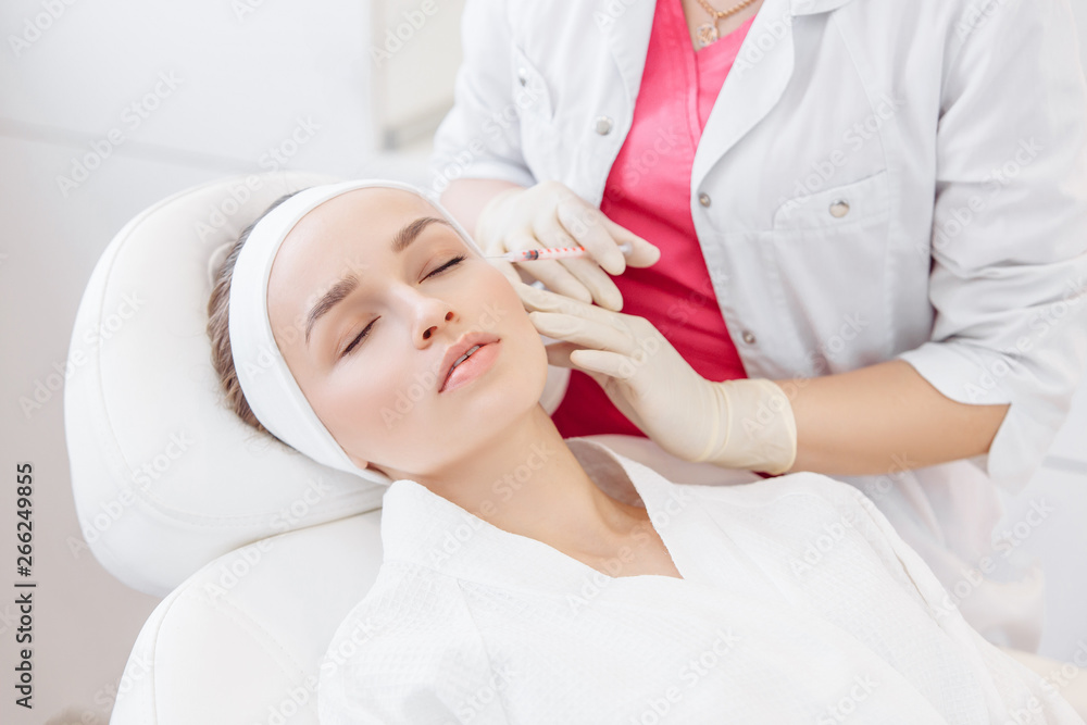 Close-up master cosmetologist makes injection of hiluronic acid in the face of a beautiful young woman. The concept of modern anti-aging procedures in the beauty salon Close-up master cosmetologist makes injection of hiluronic acid in the face of a beautiful young woman. The concept of modern anti-aging procedures in the beauty salon
