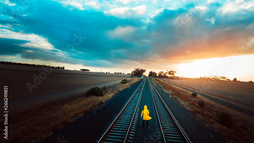 Person in Yellow Jacket on Old Train Tracks With Epic Sky