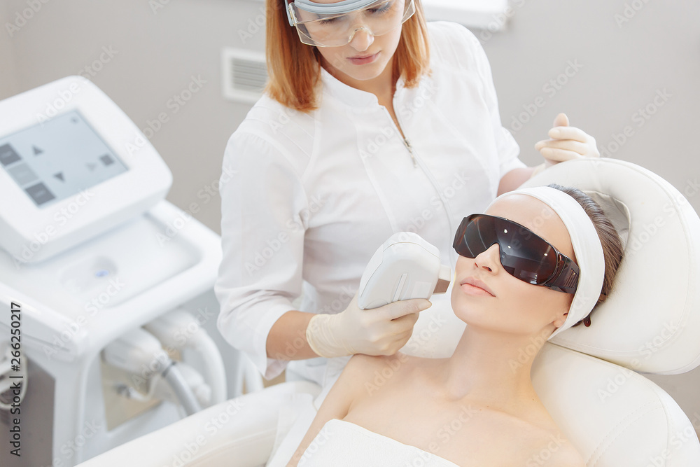 Professional cosmetologist doing an ultrasonic peeling to a client woman lying on a couch. Skin cleansing concept and modern rejuvenation technologies Professional cosmetologist doing an ultrasonic peeling to a client woman lying on a couch. Skin cleansing concept and modern rejuvenation technologies
