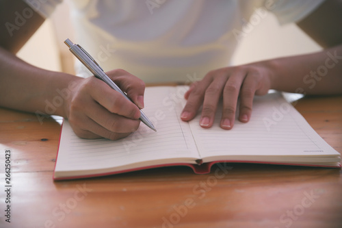 Woman hand with pen writing on notebook.