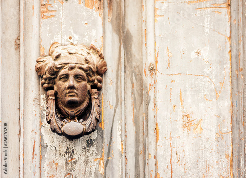 Exterior vintage door knocker metal circle on a wooden door of an ancient building in Catania, Sicily, Italy.