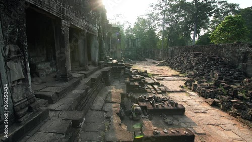Sliding view of picturesque ruins of ancient Bayon temple and jugnle behind them. It was built in 12th century by khmer civilization. Sunlight. Angkor Wat complex. Cambodia photo