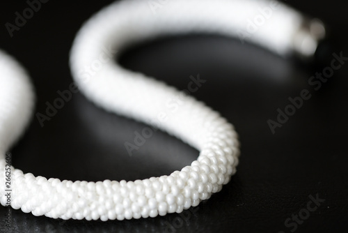 White long beaded necklace on a dark backgroun close up