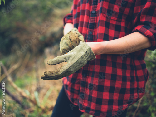 Young woman putting on gardening gloves