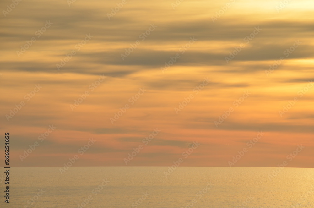 ocean sunset scene with orange and yellow clouds with a burnished sky and calm ocean off Glenelg South Australia