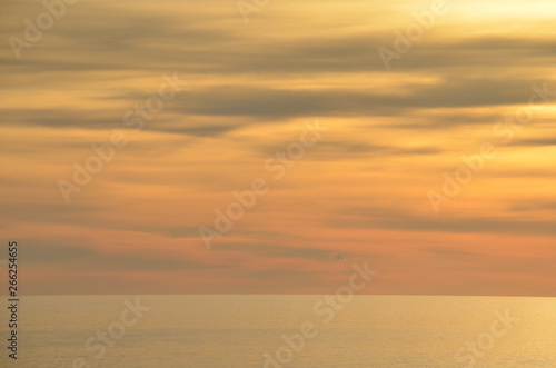 ocean sunset scene with orange and yellow clouds with a burnished sky and calm ocean off Glenelg South Australia