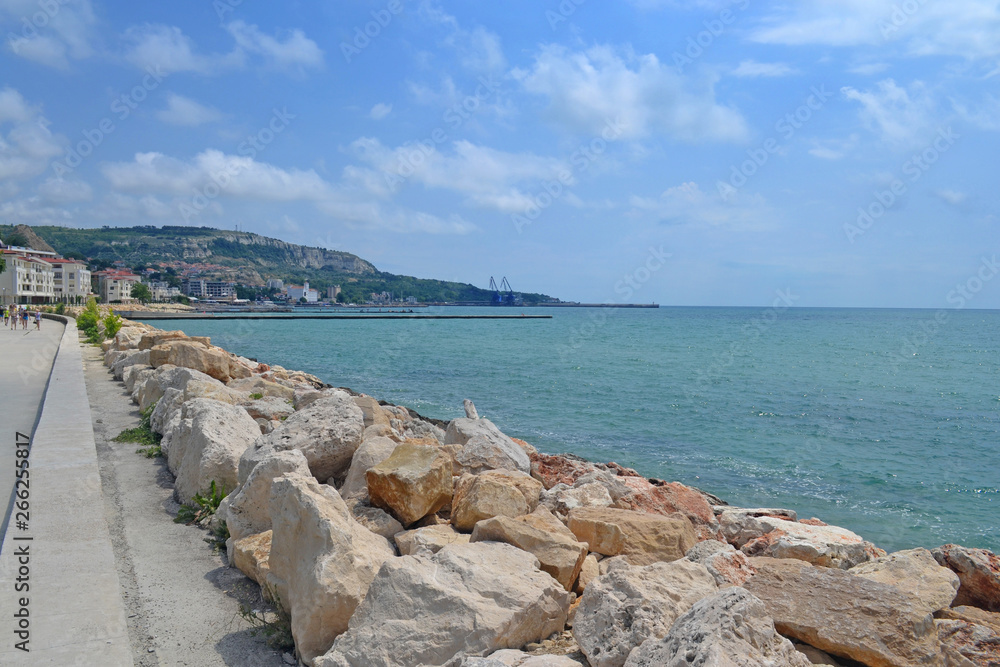 Beautiful view of the coast with an artificial mound of stones. Sunny day on the coast of Bulgaria. The road along the sea.