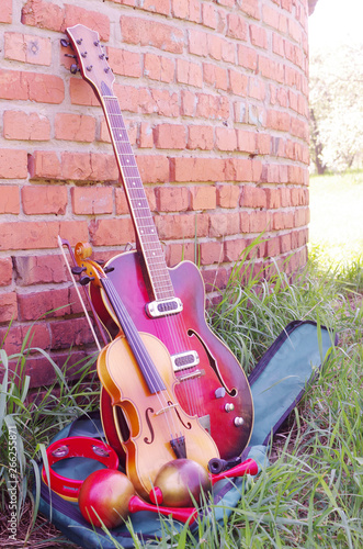 Musical instruments: guitar, violin. maracas tambourine flute on brick wall background © yrafoto