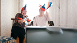Two elderly enthusiastic women watching TV in russian accessories