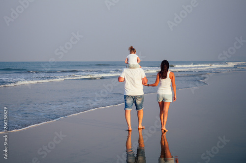 Happy family holding hands on beach and watching the sunset sunrice at Goa India ocean photo