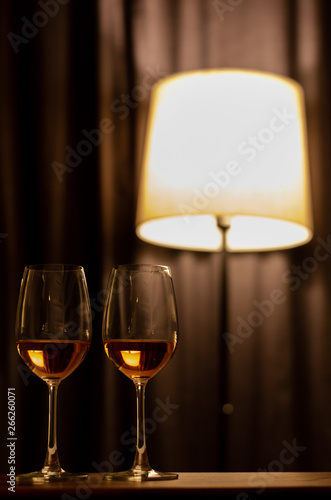 Two glasses of Rose wine on wooden table to celebrate for a couple with dark background with the lamp in the house.