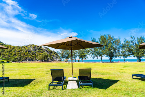 Umbrella and chair on the green grass nearly sea beach © siraphol