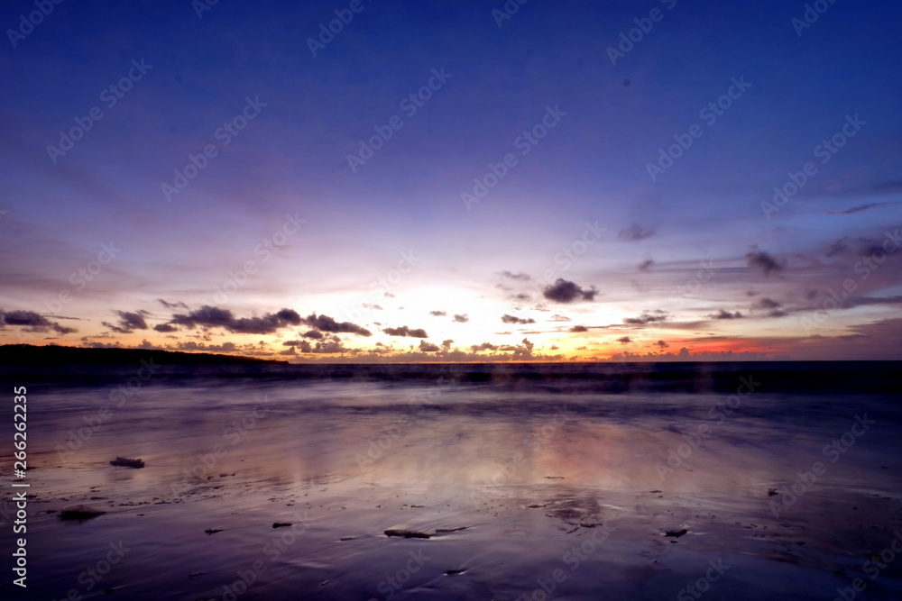 the beauty of Jimbaran beach in Bali Indonesia at dusk with the sun disappearing
