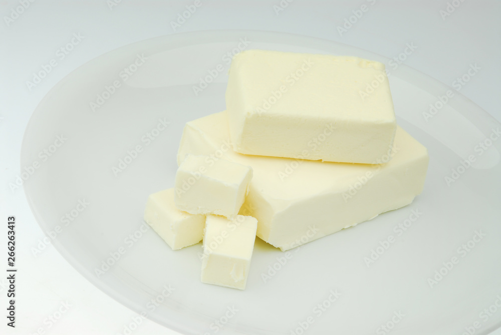 Piece of fresh organic butter on the plate isolated on a gray background in close-up Piece of fresh organic butter on the plate isolated on a gray background in close-up
