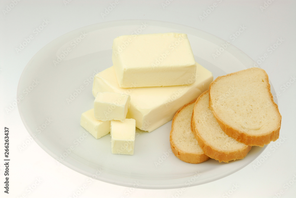 Butter and slices of bread are lying on a plate on a gray isolated background