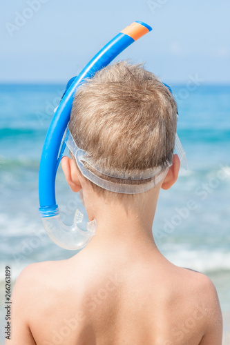 Young boy in snorkelling mask at beach. Back view