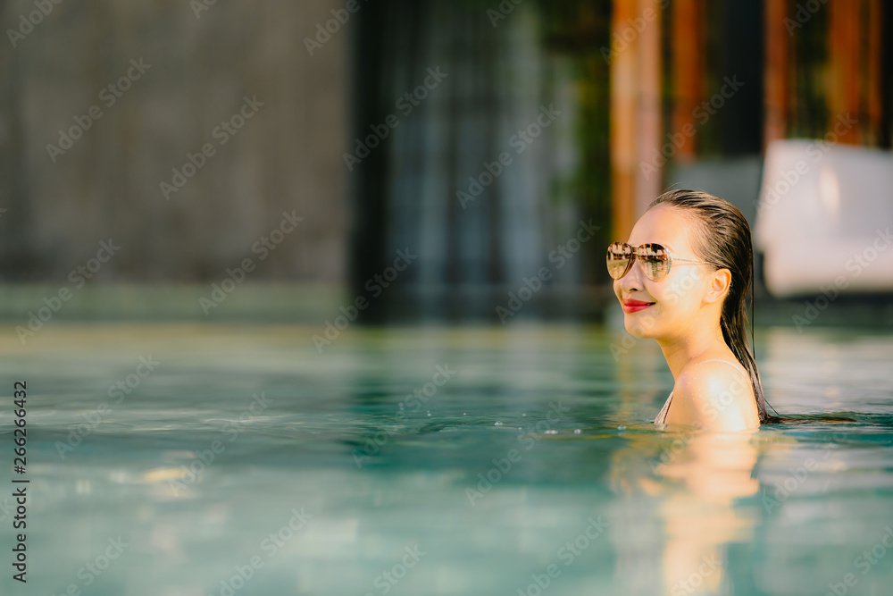 Portrait beautiful young asian woman smile happy relax around swimming pool in hotel resort for leisure