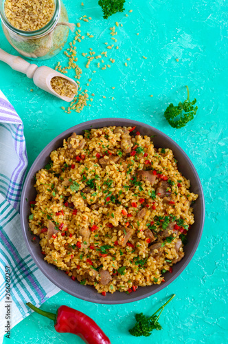 Bulgur with chicken and vegetables. Delicious healthy warm salad on a bright background. Bulgur pilaf. Top view, flat lay.