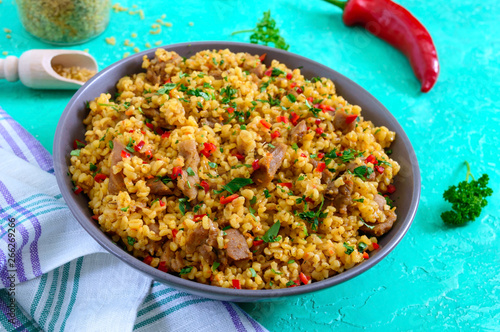 Bulgur with chicken and vegetables. Delicious healthy warm salad on a bright background. Bulgur pilaf. Close up