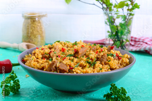 Bulgur with chicken and vegetables. Delicious healthy warm salad on a bright background. Bulgur pilaf