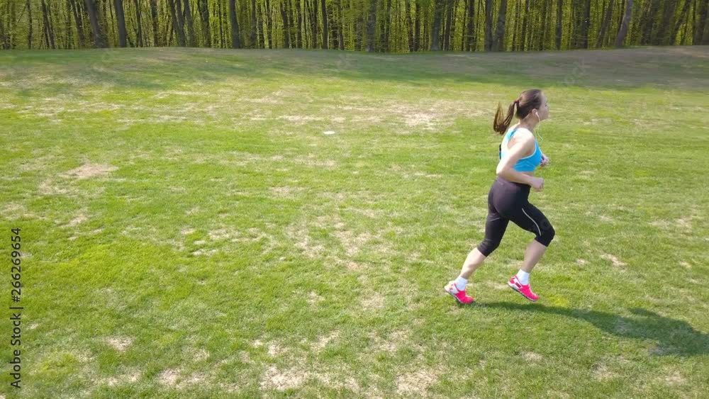 4K. Aerial. Woman fitness runner run on spring green field. 4K. Aerial. Woman fitness runner run on spring green field.