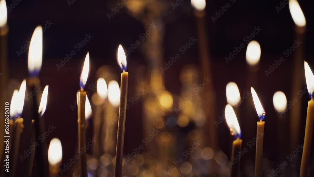 Many candles burning in the night temple. Abstract candles background. Yellow candle flames glowing on blur dark background in church. Many candles burning in the night temple. Abstract candles background. Yellow candle flames glowing on blur dark background in church.