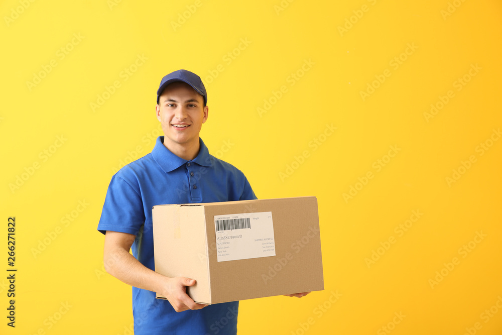Delivery man with box on color background - obrazy, fototapety, plakaty 