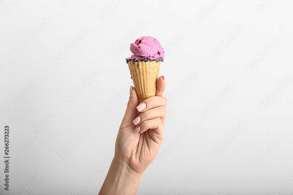 Female hand with tasty ice cream on light background Female hand with tasty ice cream on light background