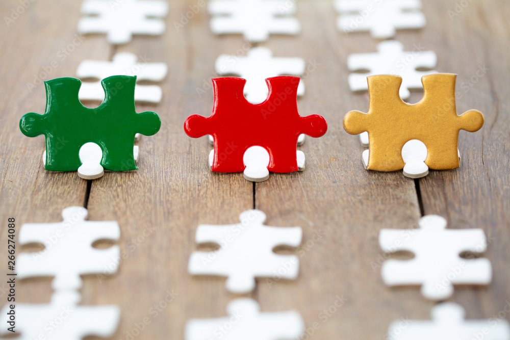 Fototapeta premium piece of Red green and gold jigsaw puzzle On the old wood And green background. teamwork concept. symbol of association and connection. business strategy.