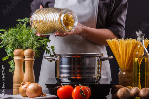 young woman in a gray apron preparing pasta photo