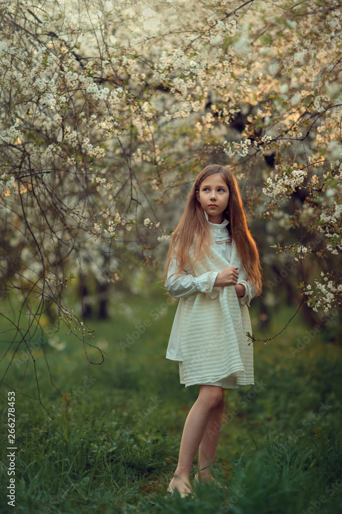 Portrait of a girl in white dress in blooming garden