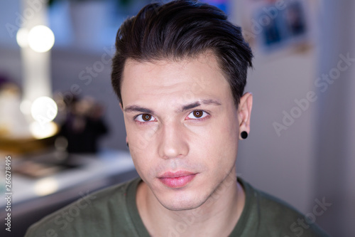 Handsome shaved dark-haired guy sitting in bright studio lights