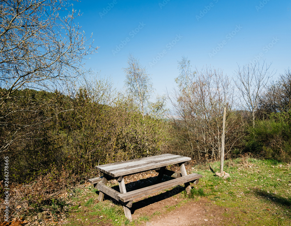 Obraz premium Resting table chair for hikers in forest with clear blue sky Vosges mountains