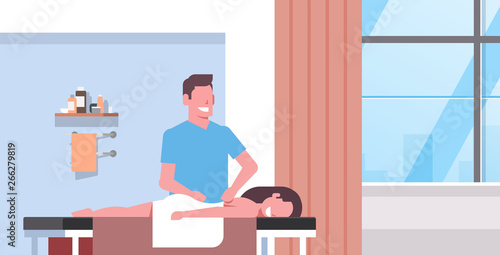 girl having back massage professional masseur massaging patient body woman relaxing lying on table medical clinic interior treatments concept horizontal